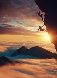 Low angle view of silhouette men rock climbing