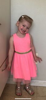 Portrait of a smiling girl standing against pink wall