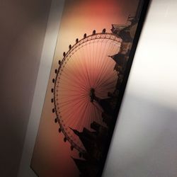 Illuminated ferris wheel in city against clear sky