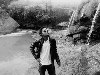 Young man exhaling smoke while standing by stream