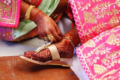 Close-up of woman wearing anklet to bride during wedding