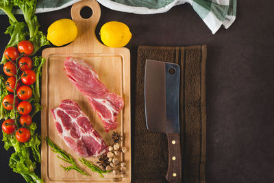 Directly above shot of red meat with vegetables and cutting board on table