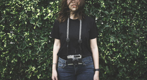 Full length of young woman standing against plants