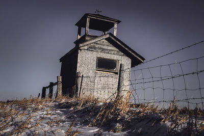 Abandoned house on land  against sky during winter