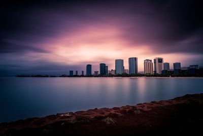 Sea and buildings against sky during sunset