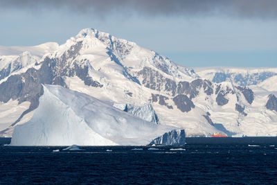 Scenic view of sea and snowcapped mountains against sky