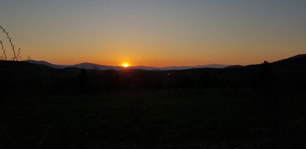 Scenic view of silhouette mountains against clear sky during sunset