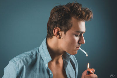 Portrait of man smoking cigarette against gray background