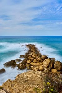 Scenic view of rocks on beach against sky