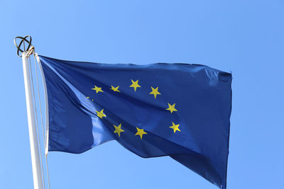 Big european flag with yellow stars and blue sky on background