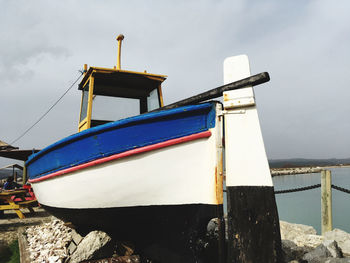 Ship moored on wooden post at beach against sky