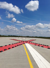 Cross shape on airport runway against sky