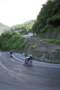 Man riding bicycle on road against mountain