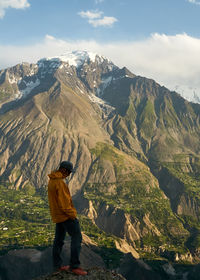 Rear view of man standing on mountain against sky