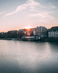 River by buildings against sky during sunset