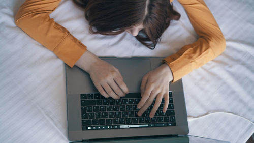Directly above shot of woman using laptop on bed