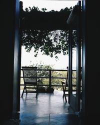 Railing by house against sky seen through window