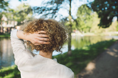 Rear view of woman with hand in hair standing at park