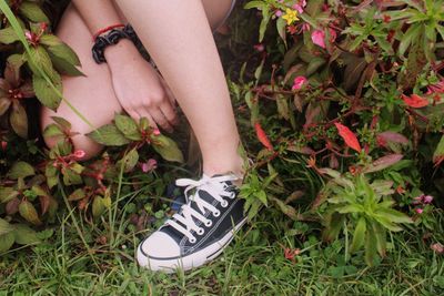 Low section of woman standing by flowering plants