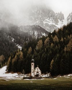 Scenic view of trees, mountains and a church against sky during winter