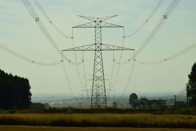 Low angle view of electricity pylon on field against sky