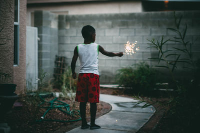 Rear view of boy standing against wall