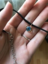 Cropped hand holding chain with pendant