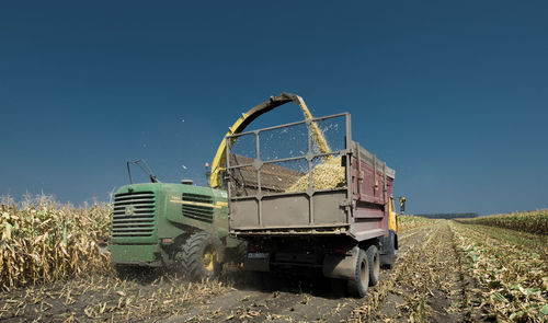 Combine harvester on field against blue sky