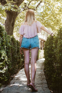 Back view of a blonde woman walking in a park in nature