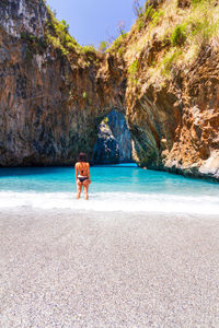 Rear view of man on rock at beach