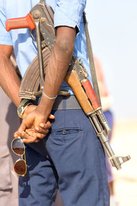 Midsection of police man holding rifle