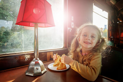 Portrait of young woman with lamp at home