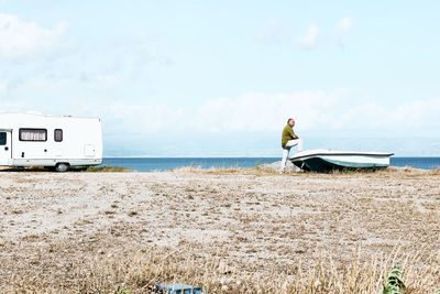 Man on the beach near the boat and white camper parked by the sea. sicily. ionian sea.