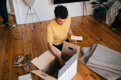 High angle view of man removing novels from cardboard box at new home