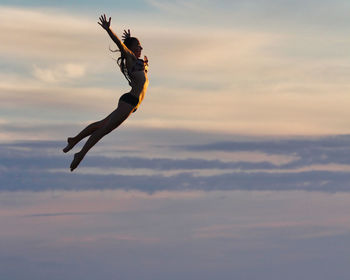 Low angle view of person jumping against sky