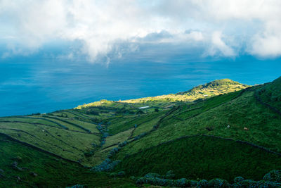 Scenic view of mountain by sea against sky