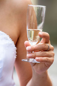 Midsection of bride holding wineglass