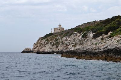 Lighthouse by sea against sky