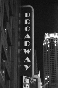 Low angle view of illuminated sign on street against buildings at night