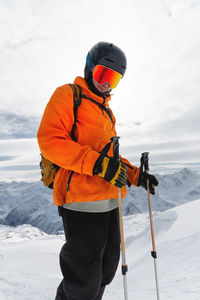 Portrait of a male skier at the top against the backdrop of epic mountains in the clouds.