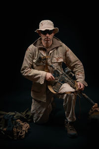 Man holding rifle against black background