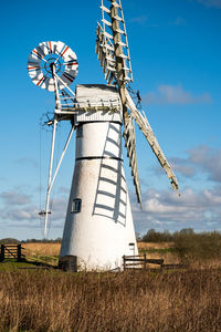 Low angle view of windmill on field against sky