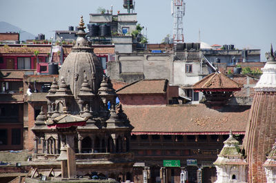 Statue amidst buildings in city against sky