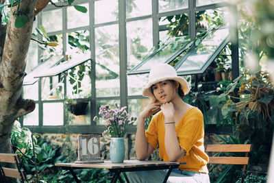 Portrait of young woman wearing hat while sitting at outdoor cafe