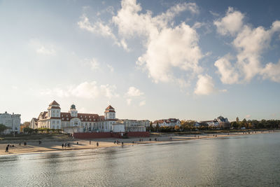 Sea by city buildings against sky