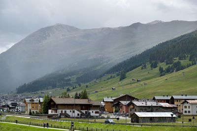 Houses on field by mountains against sky