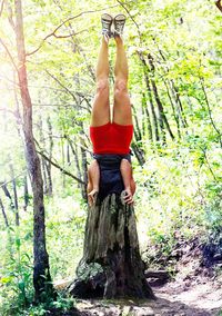 Full length of woman standing on tree trunk in forest