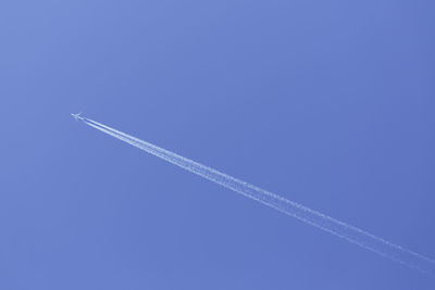 Low angle view of vapor trail against blue sky