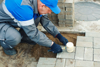 Bricklayer lays paving slabs outside. working man performs landscaping. builder lays out sidewalk