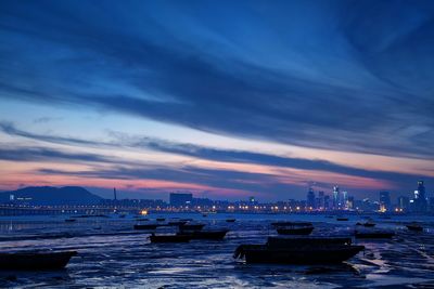 Boats moored at beach against cloudy sky during sunset